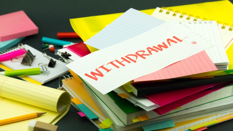 'Withdrawal' hand written note laying on pile of folders and documents