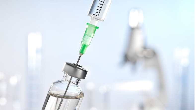 Syringe drawing vaccine from a bottle