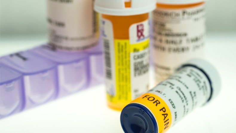 horizontal image of pain medication prescription bottles, weekly pill organizer on white. shallow depth of field with room for copy - Image 