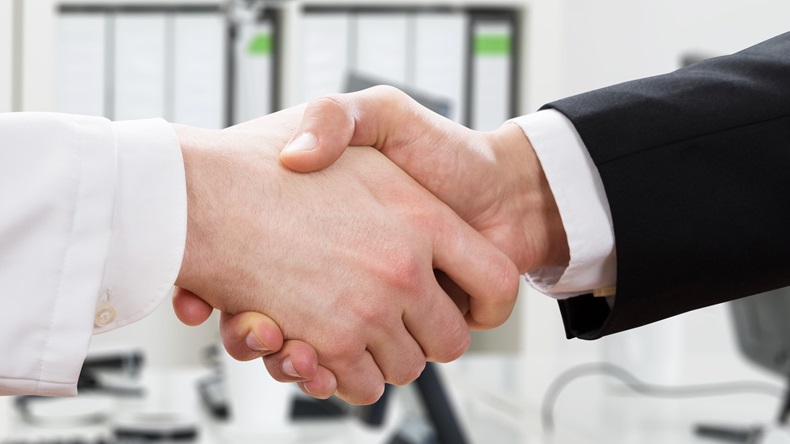 Close-up Of Doctor And Businessman Shaking Hands In Office