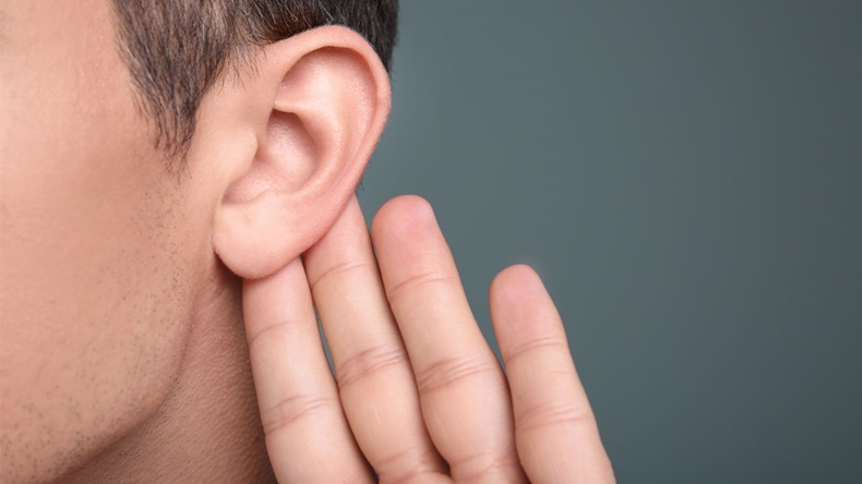 Man with hearing problem on grey background, closeup