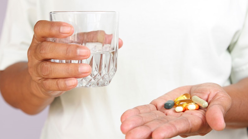 Woman holding a glass of water And in the hands are medicines.