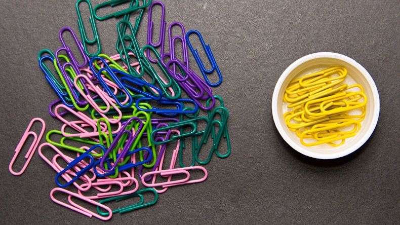 The concept of order and chaos. Chaotic disorganized colorful paper clips and to order the yellow paper clip