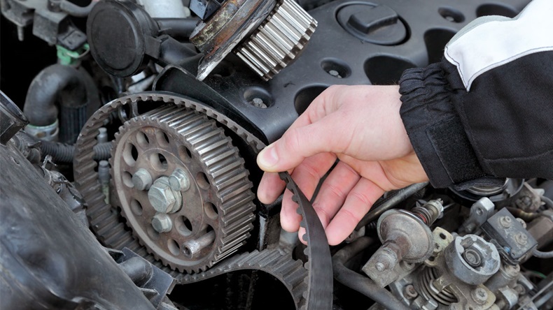 Car mechanic replacing timing belt at camshaft of modern engine - Image 