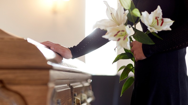 people and mourning concept - woman with white lily flowers and coffin at funeral in church - Image 
