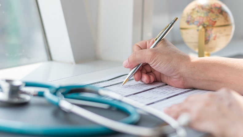 Physician doctor writing on medical health care record, patients discharge, or prescription form paperwork in hospital clinic - Image 