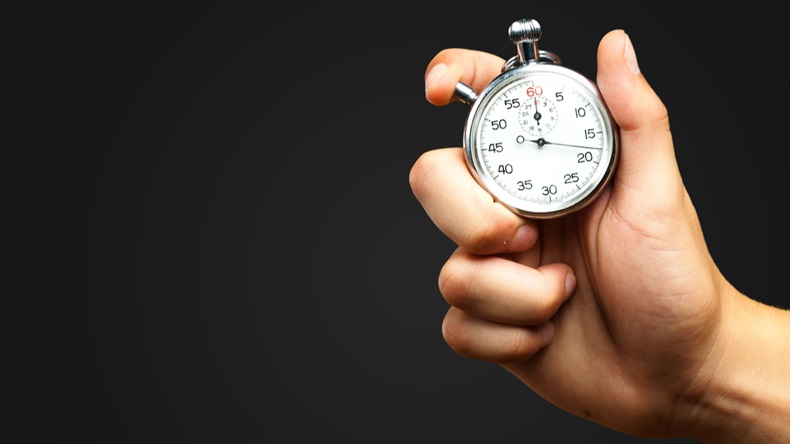 Close Up Of Hand Holding Stopwatch against a black background