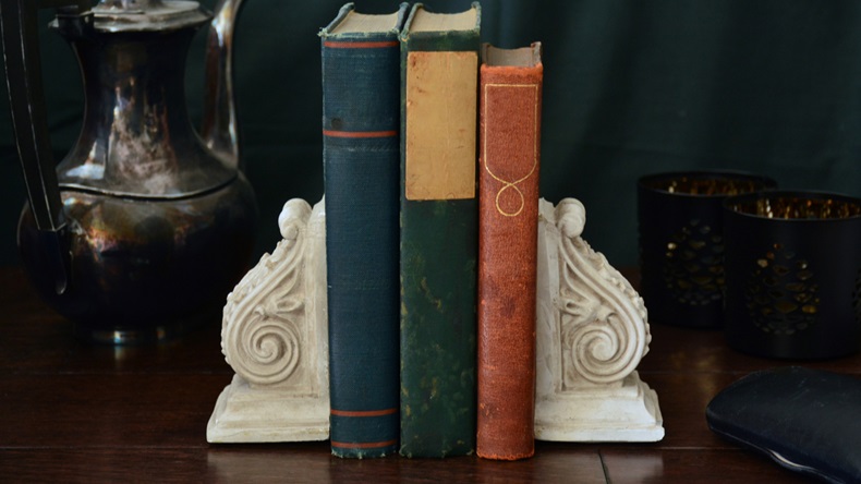 Vintage books enclosed by old fashioned bookends with a moody dark background