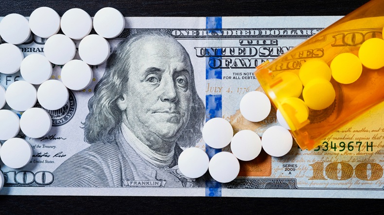 White pills spilling from prescription medicine bottle onto US currency