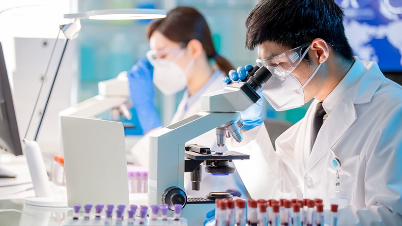 Microbiologist, biotechnology researcher, or medical worker looking into microscope in the lab