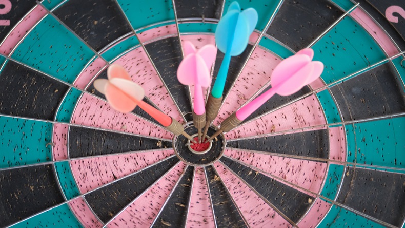 Four darts arrows hitting in the target center dartboard. Success business goal concept