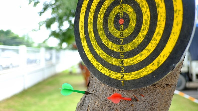 Dartboard on a tree background.the arrows miss target.