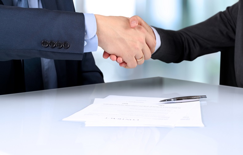 Close-up image of a firm handshake between two colleagues after signing a contract