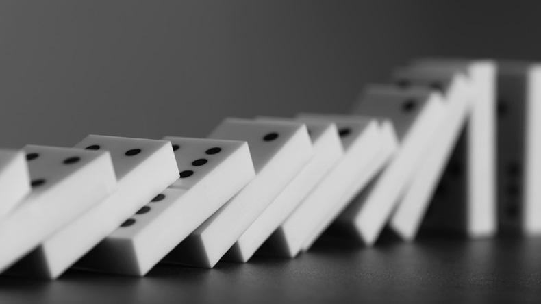 Dominoes falling on gray background