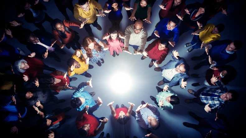 Business people forming circle around bright light