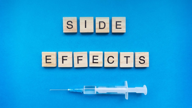 Side effects sign with wooden letters and a syringe on blue background. COVID-19 vaccination risks concept