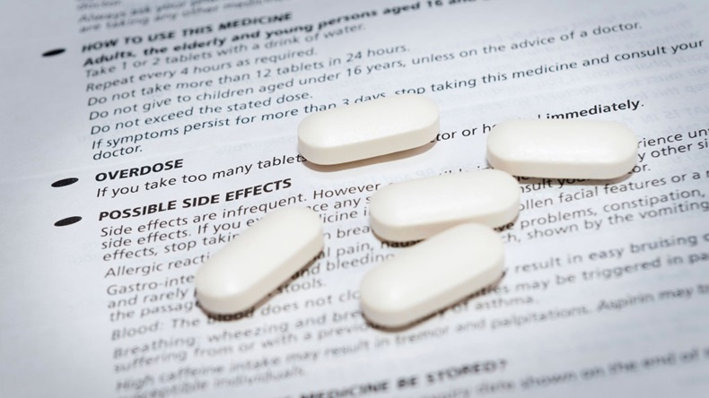 White pills on leaflet about possible side effects and overdose