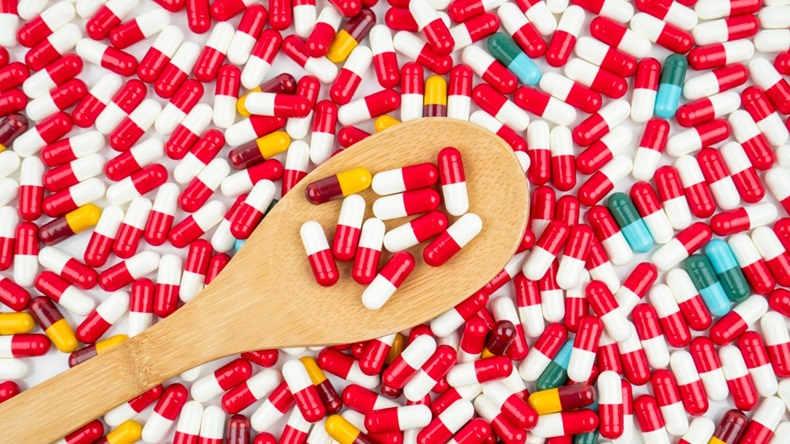 Colorful of antibiotic capsules pills and wood spoon on white background.