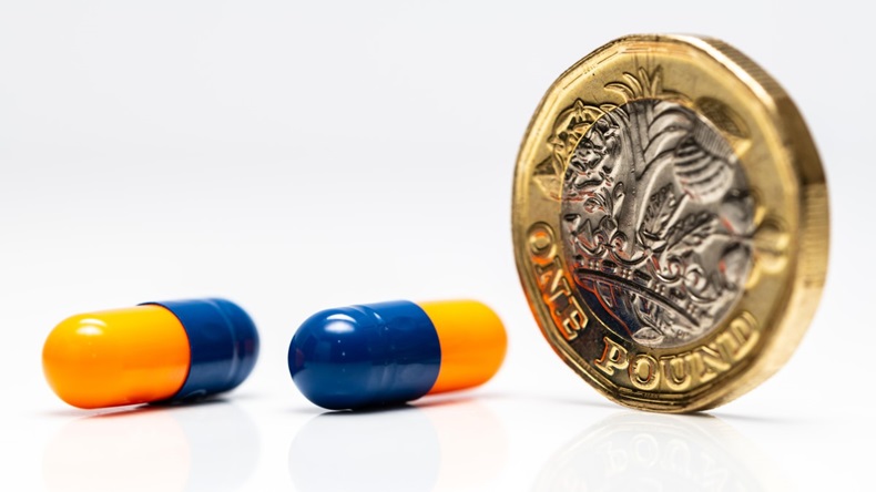 Blue & Orange drug medicine pills colored capsules closeup with pound coin on white background