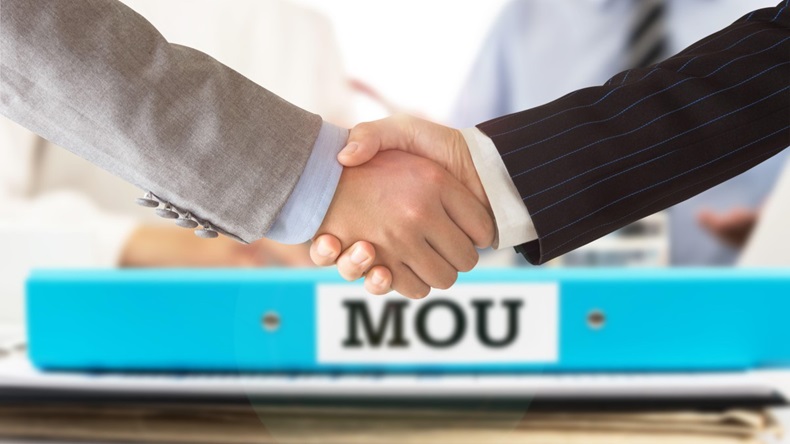 Businessman handshake on mou - memorandum of understanding with legal document contract papers after agreement.