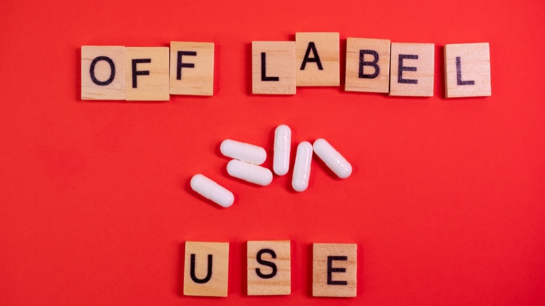 Words off label and white capsules or pill drugs on colored red paper texture background. 