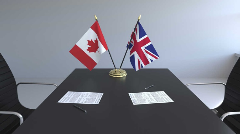 Flags of Canada and Great Britain and papers on the table.
