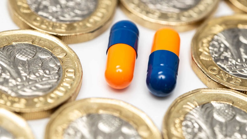 Blue & Orange drug medicine pills colored capsules closeup with pound coin on white background