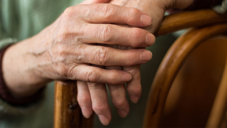 two hands of an elderly woman sitting on a chair