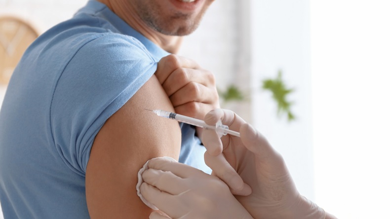 Doctor vaccinating male patient in clinic, closeup