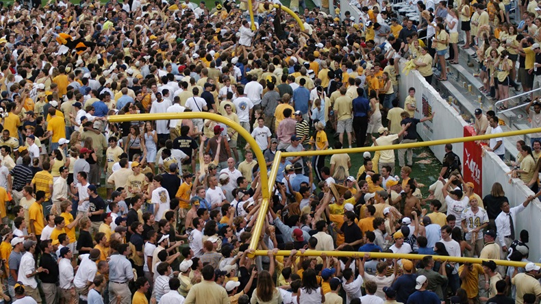 Students at a college game tearing down the goalposts