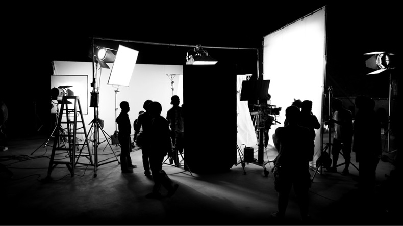 Silhouette images of video production behind the scenes or b-roll or making of TV commercial movie that film crew team lightman and cameraman working together with director in big studio 