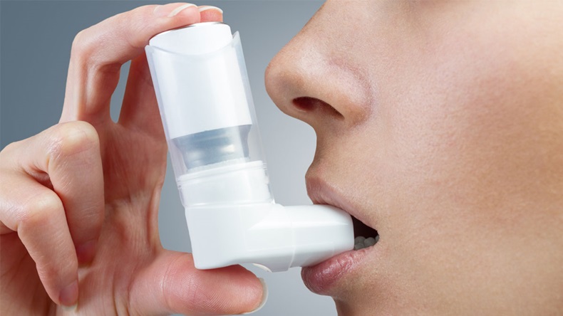 Woman uses an inhaler during an asthma attack, close-up