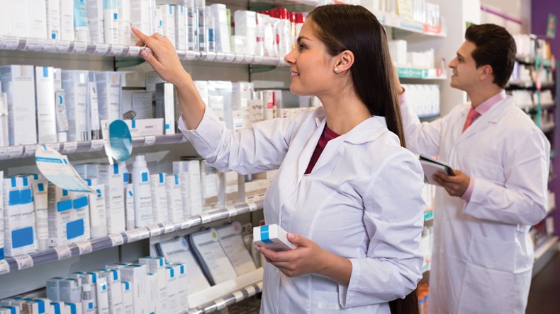 Smiling pharmacist and indian pharmacy technician posing in drugstore