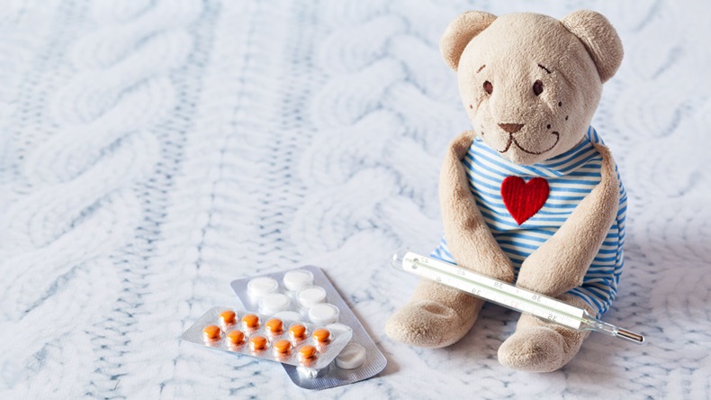 children's soft toy teddy bear with pills takes the temperature of a mercury glass thermometer. child' disease.