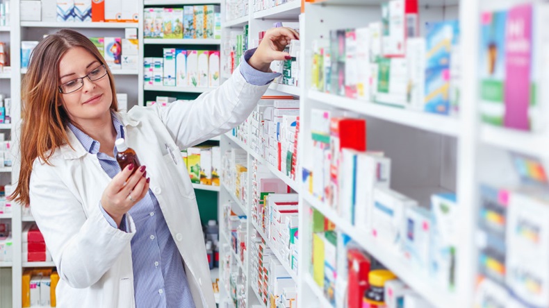 Woman pharmacist holding prescription checking medicine in pharmacy (or drugstore