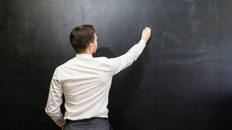 Man in suit pointing something on chalkboard,back view,isolated.Copyspace blank.Teacher writing on black board - Image 
